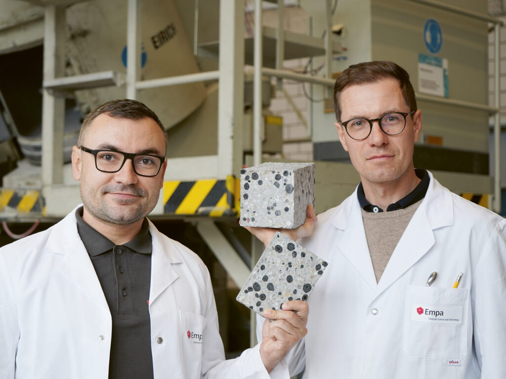 Beton ohne Emissionen: Empa-Forscher Mateusz Wyrzykowski (rechts) und Nikolajs Toropovs ersetzen herkömmliche Gesteinskörnungen durch Pellets aus Pflanzenkohle und loten damit das Potenzial von CO2-neutralem oder gar CO2-negativem Beton aus. (Quelle: Empa)